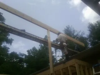Carpenter setting a ridge beam over a new addition frame — Ice Dam Removal by Roofing Brothers in Ellenwood