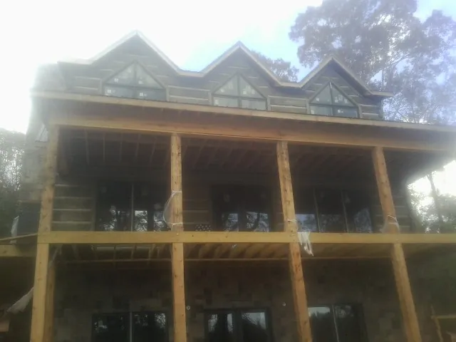 Dormers and porch framing on a large log home under construction — Roof Coating work by our crew in Ellenwood