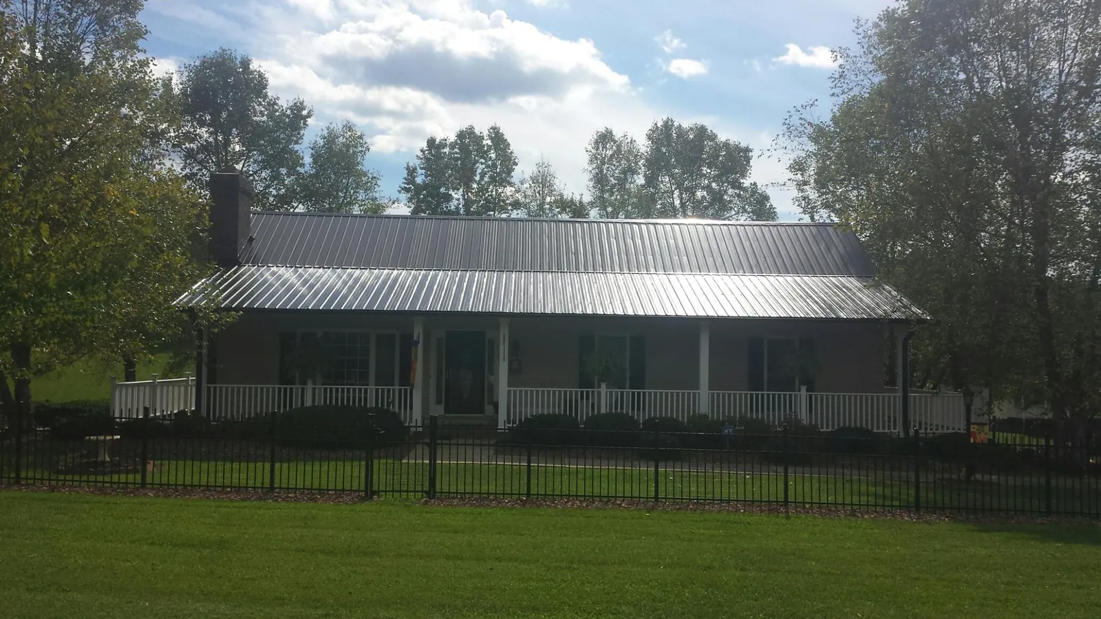 Gray metal roof on a brick ranch with a full width front porch — Gutter Guard Installation work by our crew in Ellenwood