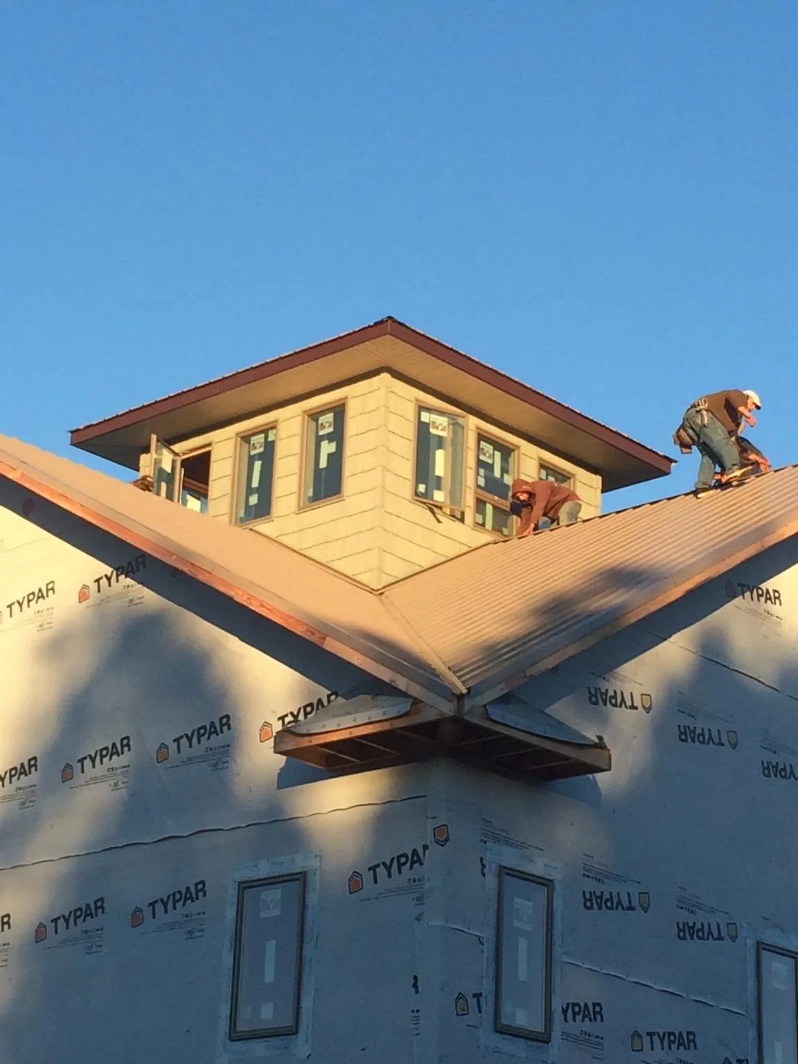 Roofers working around a rooftop cupola on a new metal roof at sunset — Roof Waterproofing in Ellenwood by Roofing Brothers